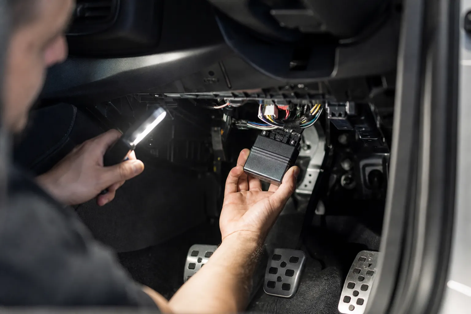 Technician installing a CAN immobiliser module under the dashboard